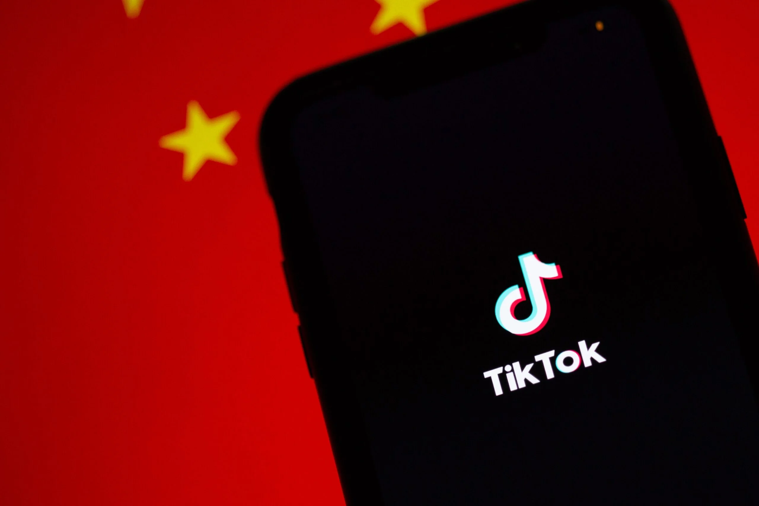 Illustrasjon av mobiltelefon med TikTok-logoen og det kinesiske flagget i bakgrunnen.