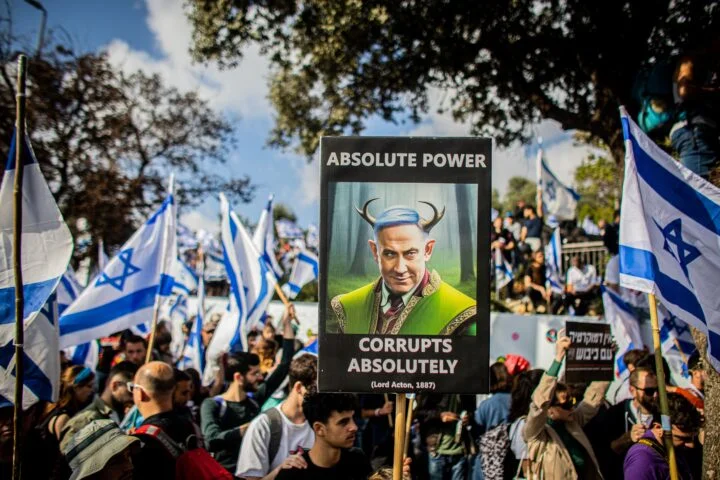 Demonstrant holder opp en plakat med en karikatur av Israels statsminister Benjamin Netanyahu tegnet som en djevel.